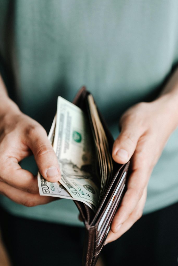 pexels-photo-4386433-4386433 Close-up of hands holding a wallet with cash, depicting financial management.